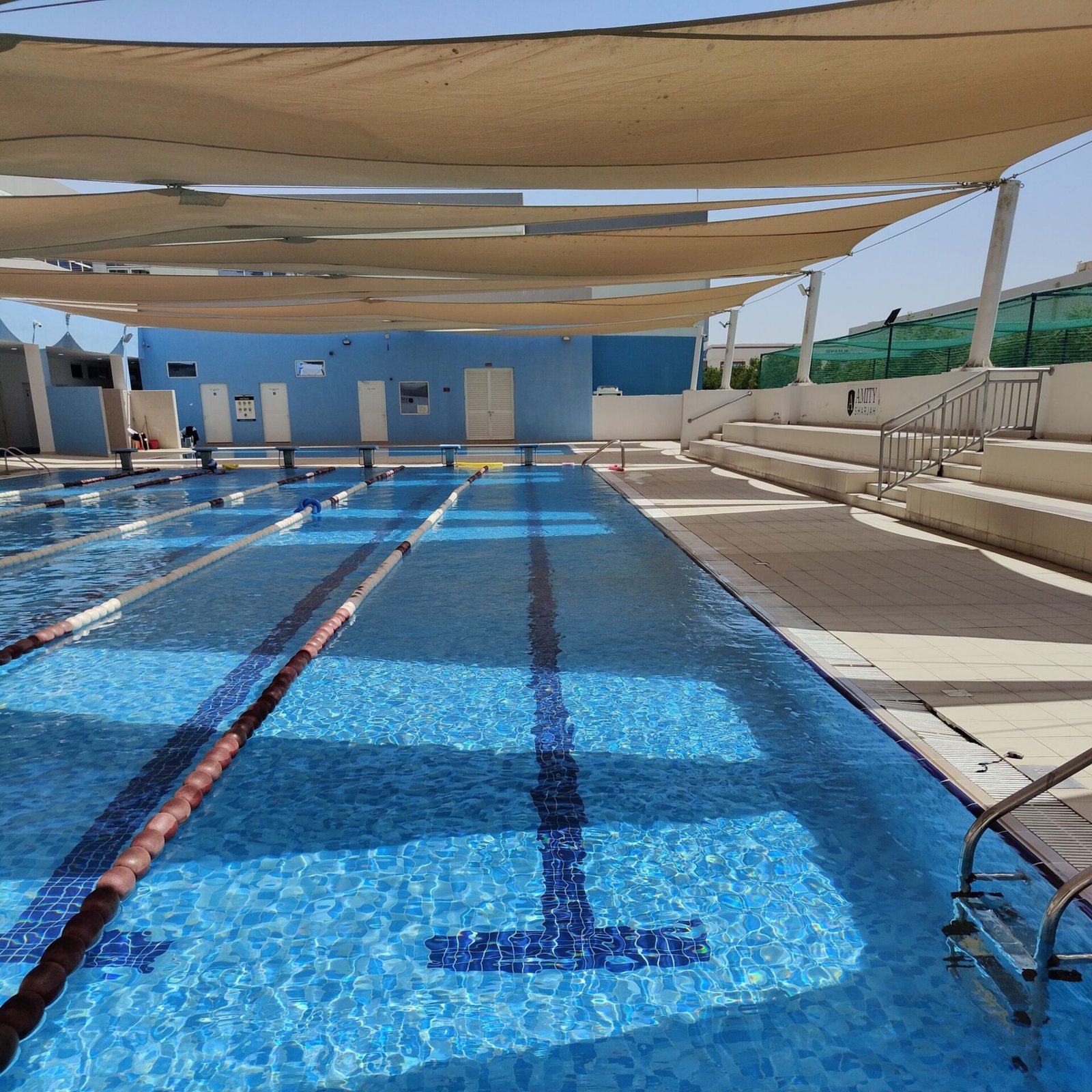 Shaded outdoor swimming pool with lanes, perfect for training or recreation, in the UAE.